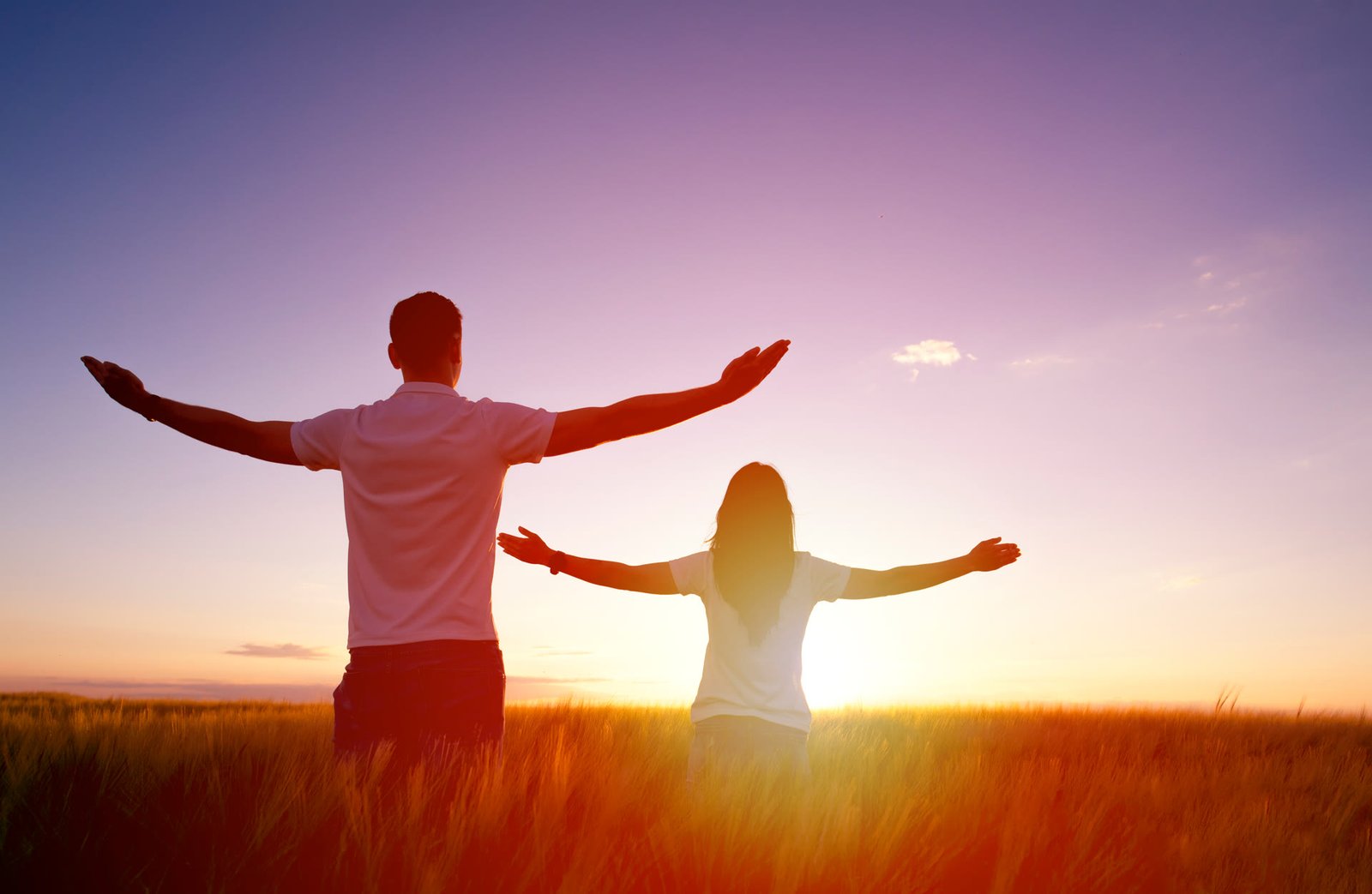 Couple libre et épanoui, bras ouverts au coucher du soleil